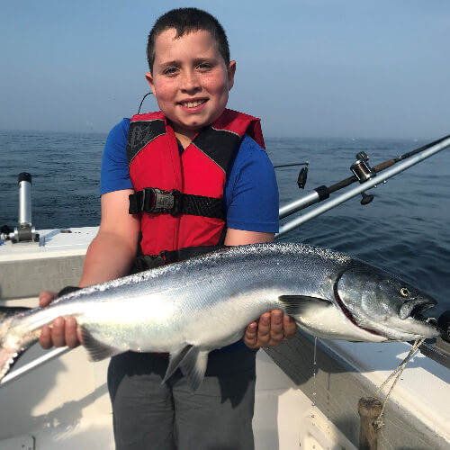 Kid holding salmon on a Lake Ontario fishing charter